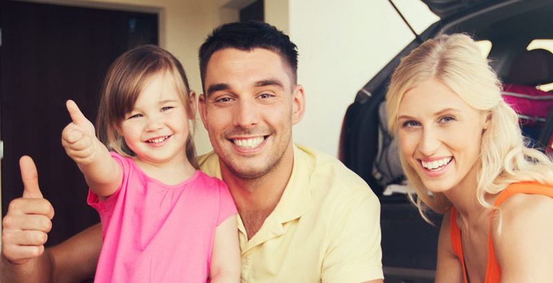 A happy family packing their car for a road trip.